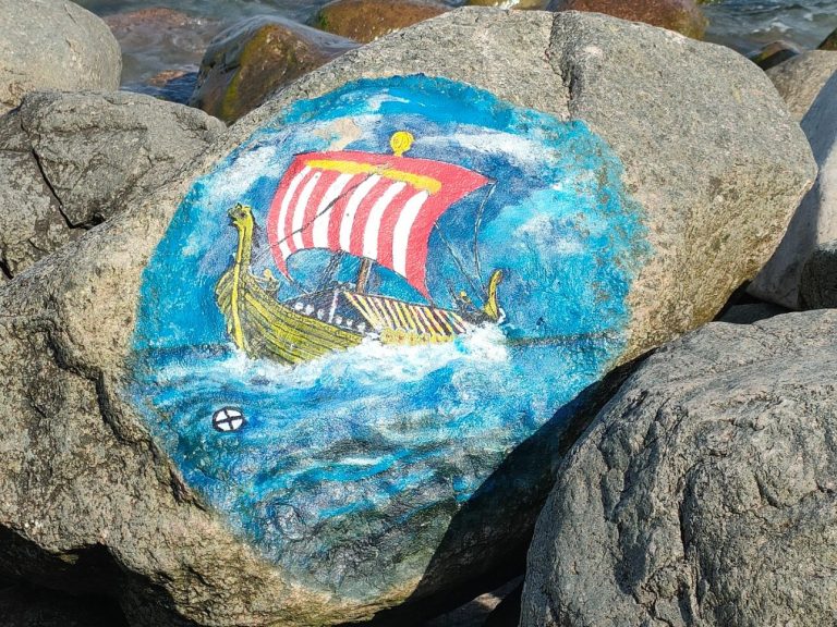 Wikingerstein Bunter Stein mit einer Drachenboot-Malerei vor einer blauen Welle.